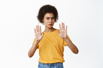 Stop. Concerned serious Black woman showing block, taboo gesture, saying no, raising palms in...