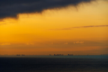 Fototapeta na wymiar silhouettes of ships at sea, dramatic seascape with sunset sky, sunlight reflected from the waves