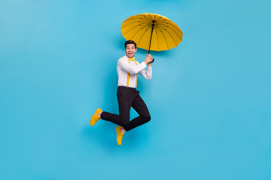 Full body photo of excited satisfied person hold umbrella fly isolated on blue color background