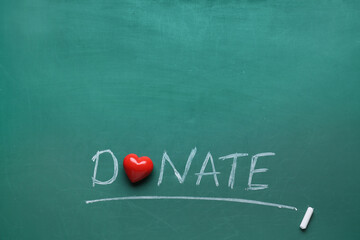 Red heart and word DONATE written with chalk on green background