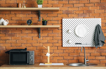 Peg board with kitchenware hanging on brick wall