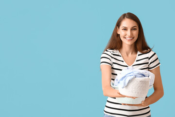 Beautiful housewife with laundry in small baskets on blue background