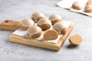 Wooden board with homemade steamed honey gingerbread with lemon icing on gray background