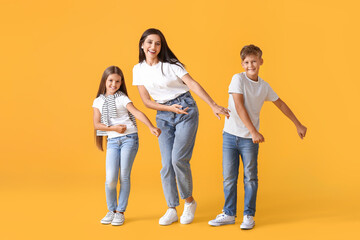 Happy dancing woman and her children on color background
