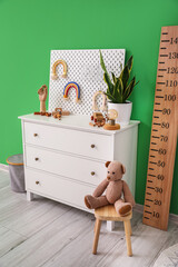 Interior of stylish children's room with commode, stadiometer and pegboard