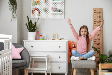 Happy little girl sitting on ottoman at home