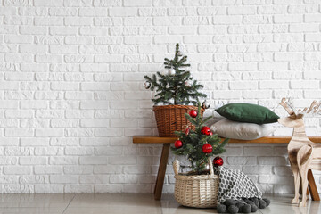 Beautiful Christmas trees near white brick wall in interior of room