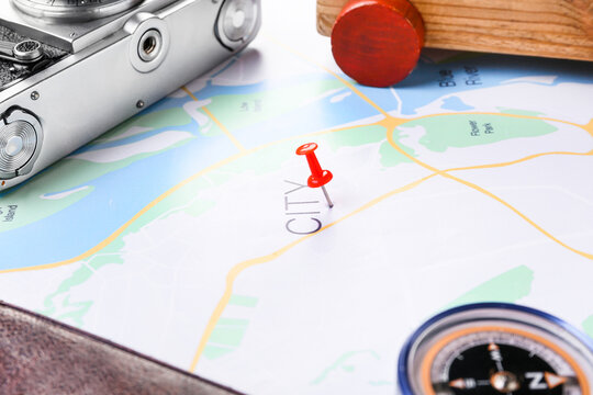 Photo camera, wooden car, compass and red pin on map, closeup