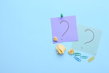 Paper sticks with question marks and clips on blue background
