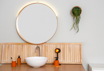 Table with sink, bath supplies and lamp near light wall