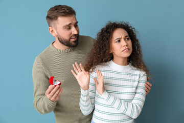 Young African-American woman rejecting marriage proposal on color background