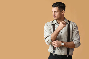 Fashionable gentleman adjusting sleeve on color background