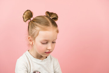 Sad little blonde girl on pink background. Valentines Day or Mothers Day concept