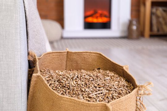 Bag with wood pellets near sofa in living room, closeup