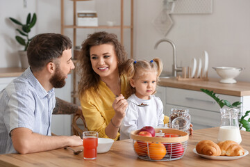 Obraz na płótnie Canvas Happy young family having breakfast in kitchen at home