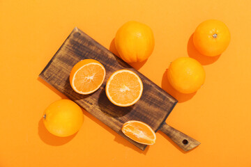 Board with fresh oranges on color background