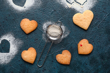 Tasty heart shaped cookies and sieve on dark background. Valentines Day celebration