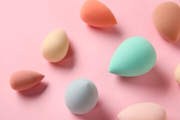 Different makeup sponges on pink background, closeup