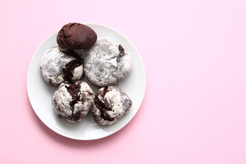 Plate with tasty chocolate brownie cookies on pink background