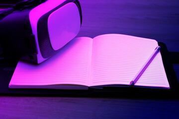Virtual reality glasses lie on an open book, space for text on a multi-colored background.
