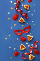 Carnival mask and Hamantaschen cookies for Purim holiday on color background