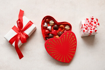 Heart shaped box with tasty chocolate candies and gifts on white background