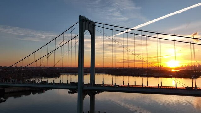 flying left around Bronx Whitestone Bridge revealing sun on horizon over NYC