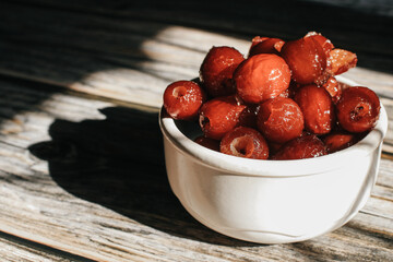 Sweet dried red date or Chinese jujube in white bowl under sunlight near window.