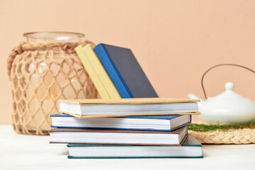 Stack of books on table near beige wall, closeup