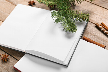 Opened books with blank pages and winter decor on wooden background, closeup
