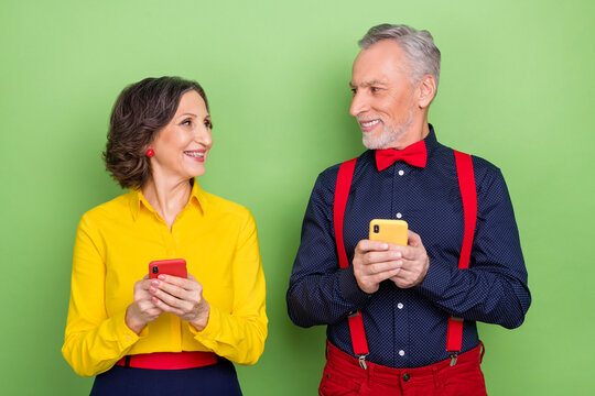 Portrait of two positive partners hold telephone fast speed connection social media isolated on green color background