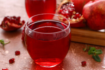 Glass of delicious pomegranate juice on red background