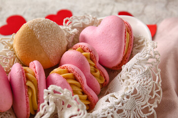 Bowl with tasty heart-shaped macaroons on light background, closeup