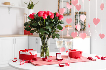 Engagement ring, glasses of champagne and gift boxes on dining table in kitchen