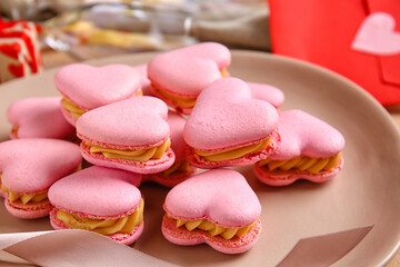 Plate with tasty heart shaped macaroons on table, closeup