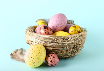 Nest with beautiful Easter eggs on blue background