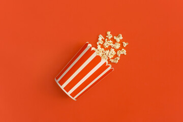 Popcorn in striped bucket isolated on red background