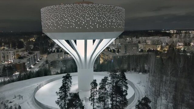 Vantaa.Finland-December 29.2021: Drone shot of the new water tower in Hiekkaharju Vantaa. Wintertime. Pretty cityscape. Nighttime. Camera slowly moving forward.