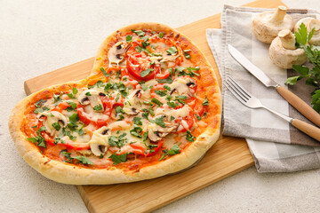 Wooden board with tasty heart-shaped pizza on light background. Valentine's Day celebration