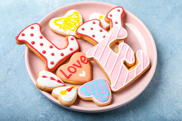 Plate with word LOVE made of cookies on blue background