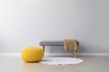 Comfortable pouf and bench with plaid near light wall - obrazy, fototapety, plakaty