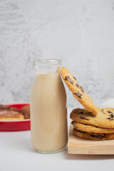 Galletas de chispas de chocolate con vaso de café con leche sobre tabla de madera