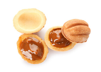 Halves of tasty walnut shaped cookies with boiled condensed milk on white background