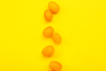 Tasty kumquat fruits on yellow background