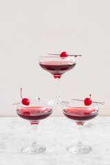 Glasses of tasty Manhattan cocktail with cherries on white background