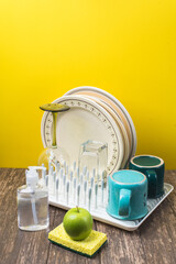 detergent and washcloth, dish dryer with clean dry dishes, on the kitchen table.