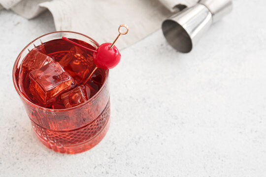 Glass of iced Manhattan cocktail on light background, closeup