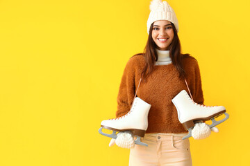 Happy woman in winter clothes and with ice skates on color background © Pixel-Shot