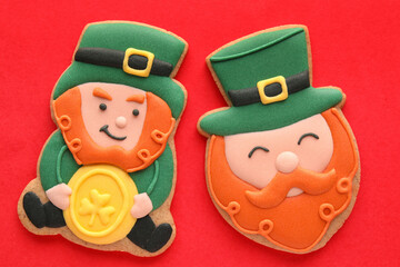Tasty decorative gingerbread cookies for St. Patrick's Day celebration on red background