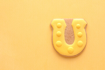 Tasty gingerbread cookie in shape of horseshoe for St. Patrick's Day celebration on green background